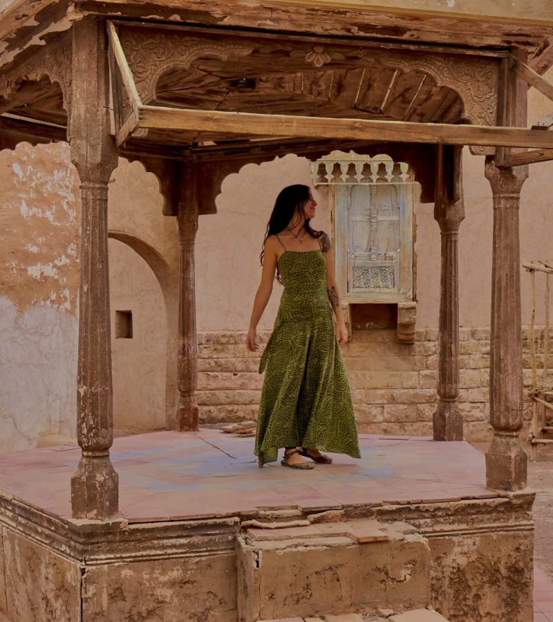 Young brunette lady dancing on old street scene between retro building on street in Marrakesh, Morocco