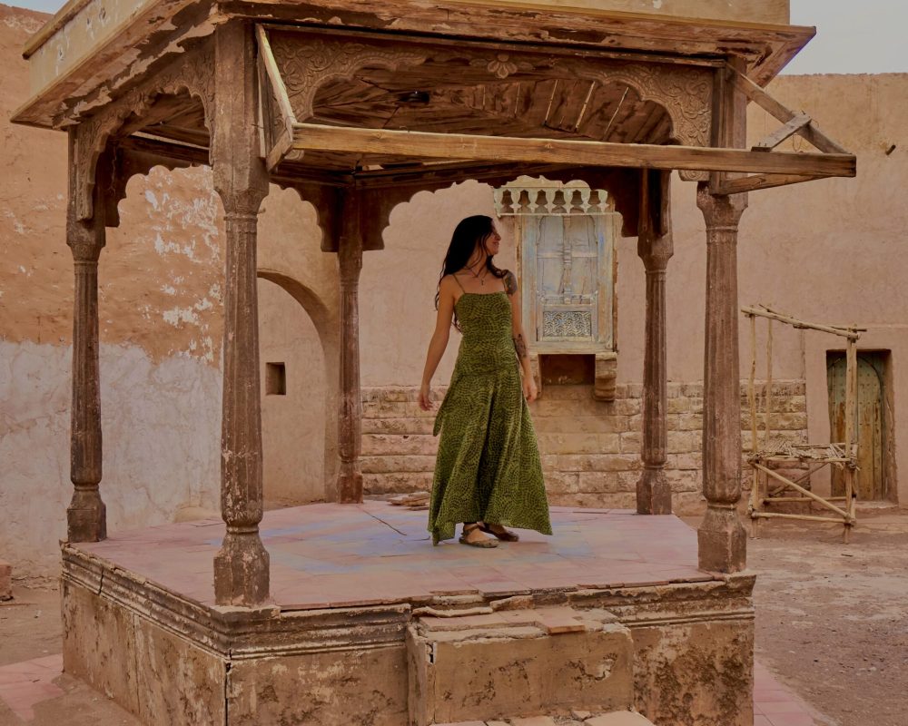 Young brunette lady dancing on old street scene between retro building on street in Marrakesh, Morocco